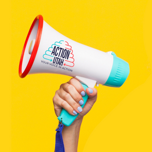 A hand with blue-painted nails holds a turquoise, white, and red megaphone against a bright yellow background. The megaphone features the logo and text Action Utah: Your Voice in Action.